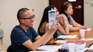Student laughing while reading A guy smiling at his books